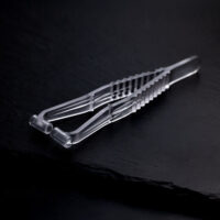 Sterile Septum Piercingzange auf schwarzem Hintergrund Transparente Septum Piercingzange aus Kunststoff auf dunklem, glattem Hintergrund